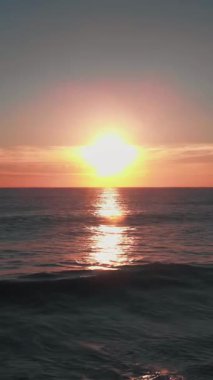 Muhteşem günbatımı manzarası. Denizde gün batımı. Bulutlu gökyüzünün inanılmaz gün batımı ışığı. Dikey video