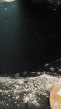 Pizzayı yuvarlayan bir kadın, ellerinizi yakın tutun. Modern mutfakta geleneksel ev yapımı pizza hazırlayan bir kadın. Dikey video