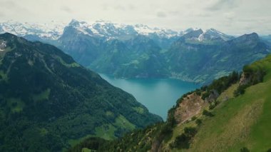 Karlı kayalık dağların manzarası ve İsviçre Alplerinde Lucerne Gölü. Lucerne Gölü 'nün turkuaz suyu ve ufukta karla kaplı dağ zirveleriyle görkemli hava manzarası.