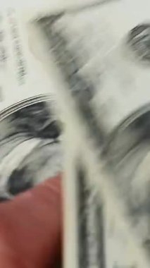 Adam dolarları sayıyor. Dikey video. ABD banknotlarını elinde tutan ve nakit paraları sayan biri var. İş ve finans kavramı