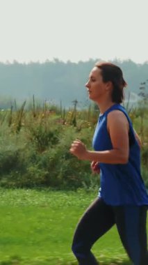 Sabah koşan bir kadın. Koşu egzersizi yapan bir kadın. Gezinti güvertesinde koşan genç aktif sporcu. Dikey video