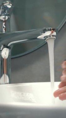 Lavaboda sabunla ellerini yıkayan biri. Modern banyodaki kadınlar ellerini köpükle yıkarlar, parmaklarını ovuştururlar, su ellerinden akar. Dikey video