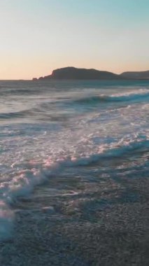 Türkiye 'de günbatımında güçlü deniz dalgaları su yüzeyine sıçrıyor ve sahile çarpıyor. Denizde rüzgarlı ve fırtınalı bir hava. Şiddetli azgın deniz. Dikey video
