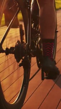 Gün batımında bisiklet tekeri dönüyor. Gün doğumunda bisiklet süren bir kadın, bisiklet teçhizatını ve bacaklarını kapatıyor. Gün batımında bisiklet üzerinde bisiklet eğitimi. Dikey video