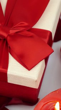 Kırmızı kurdeleli sevgililer günü hediye kutularını kapat. Romantik selamlaşma. Kırmızı şenlikli arka planda kırmızı kurdeleli hediyeler. Dikey video