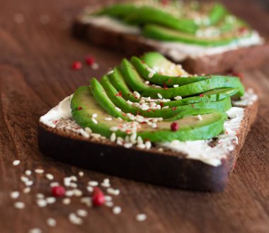 ahşap masa üzerinde avokado dilimleri ile krem peynir ekmeği