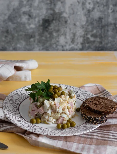 Russian winter salad on a yellow table with whole grain bread