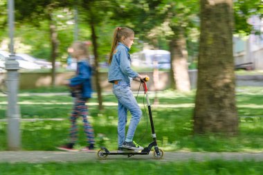 Kız mutlu bir asfalt yol boyunca bir scooter sürme