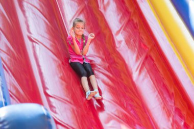 Kız yüksek yumuşak şişme trambolini aşağı akıyor