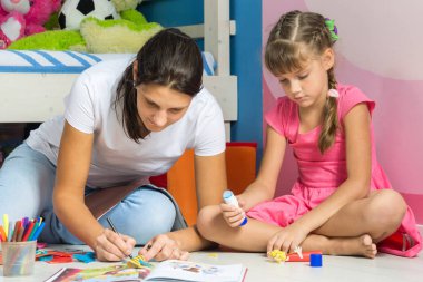 Mom and daughter sitting on the floor in the nursery and crafting crafts clipart