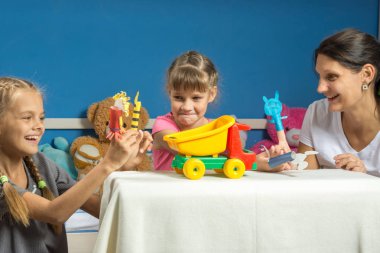 Mom plays with two daughters in a self-made finger puppet theater clipart