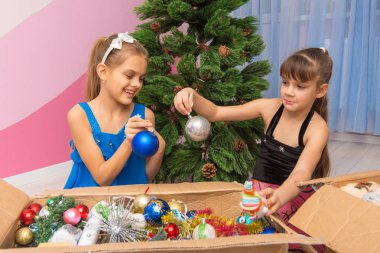 Two girls are considering balls in a box with New Year's toys clipart