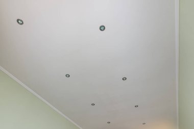 Odada sıva ve boyalı tavan, spot ışıkları takılı.