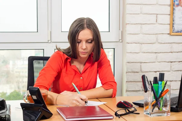An employee writes a statement at the desk in the office — Stock Photo, Image