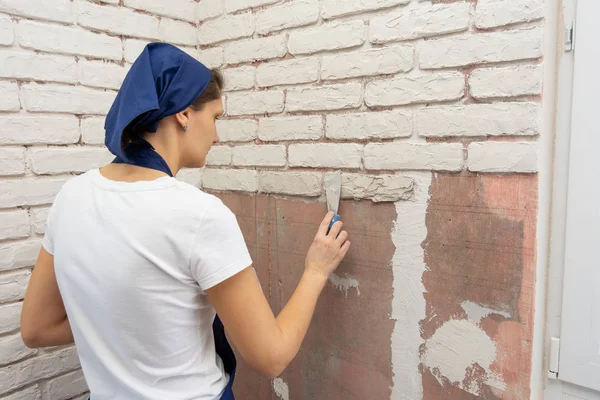 Tired girl performs work on the imitation of brickwork on the wall — Stock Photo, Image
