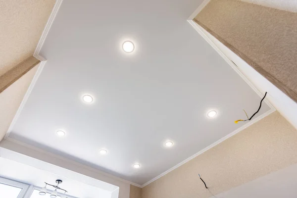 Растяжной потолок на кухне с установленными и включенными прожекторами — стоковое фото