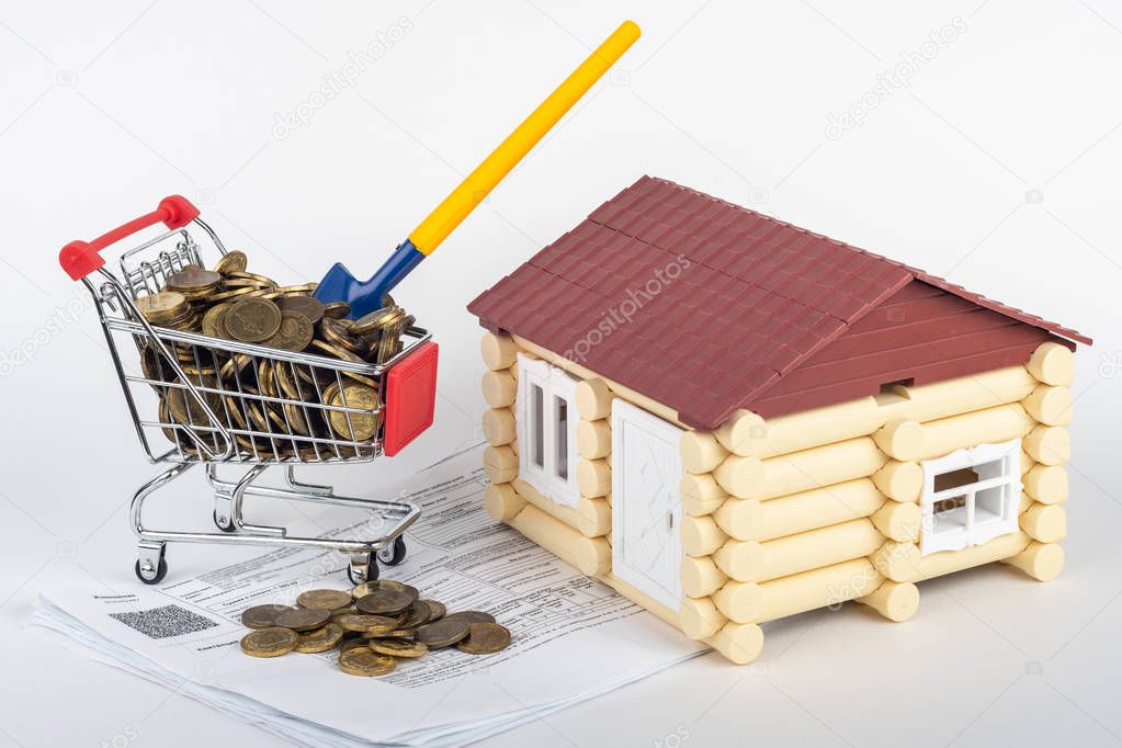 A trolley with money in the bills for an apartment, a shovel stuck in a trolley, a toy house next to it
