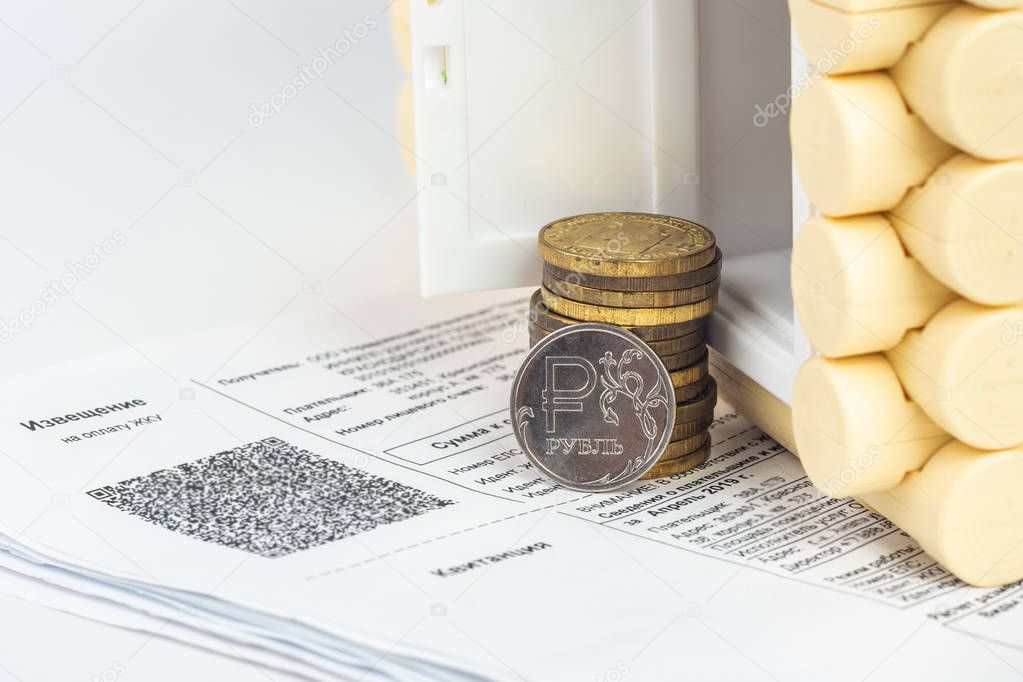 A stack of money and one ruble coin in the accounts for the apartment, in front of the door to the house