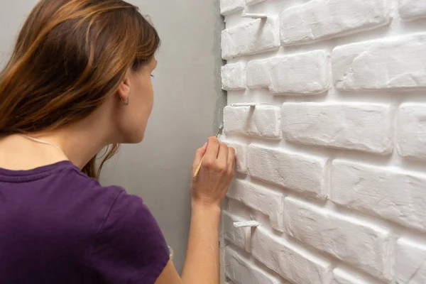 A house painter tends to paint a gray corner of the wall with a small tassel — Stock Photo, Image