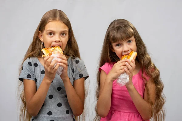 Duas meninas famintas comem pão, e olhe para a moldura — Fotografia de Stock