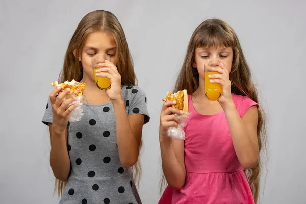 Två flickor dricker saft och äta en bulle — Stockfoto