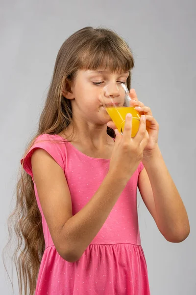 Flicka dricker apelsinjuice från ett glas — Stockfoto