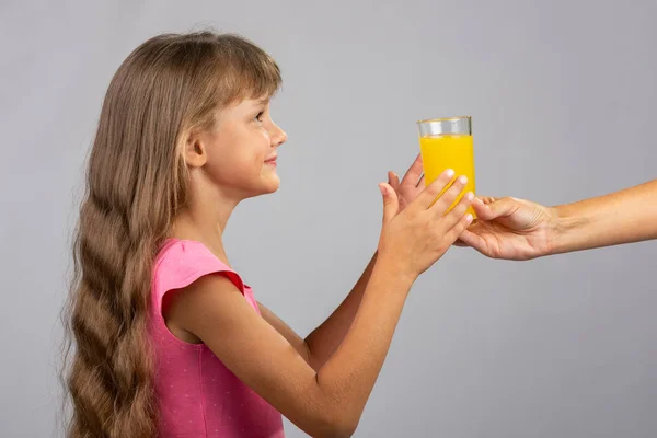 Handen håller ut ett glas apelsinjuice — Stockfoto