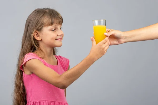 Flickan tar från hennes hand ett glas apelsinjuice — Stockfoto