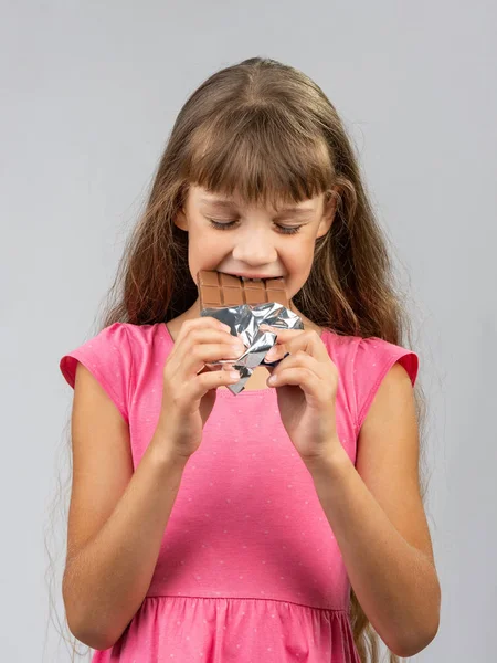 Teen girl with pleasure bites chocolate — Stock Photo, Image