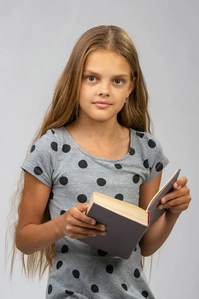 Mooi tien jaar oud meisje leest een boek en kijkt in het frame — Stockfoto