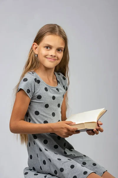 Une jeune fille de dix ans distraite de la lecture d'un livre et regarda joyeusement dans le cadre — Photo