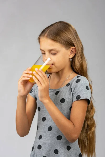 En tioårig flicka dricker saft, halv-sidig vy — Stockfoto