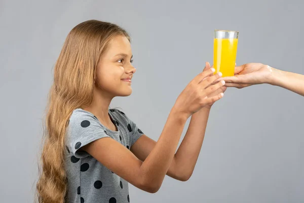 Uma menina com duas mãos toma um copo de suco da mão de outra pessoa — Fotografia de Stock