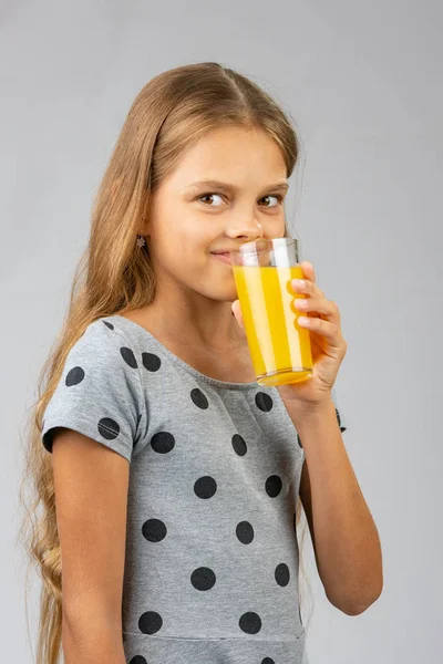 Uma menina de dez anos bebe suco, e com um sorriso olhou para a moldura — Fotografia de Stock