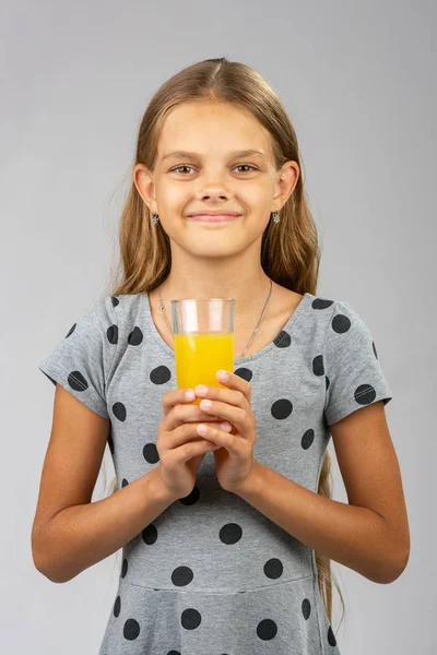 Ein Mädchen hält mit beiden Händen ein Glas Saft in der Hand — Stockfoto
