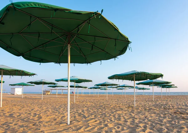 Egy elhagyatott homokos strand napernyő megnyitása naplementekor — Stock Fotó
