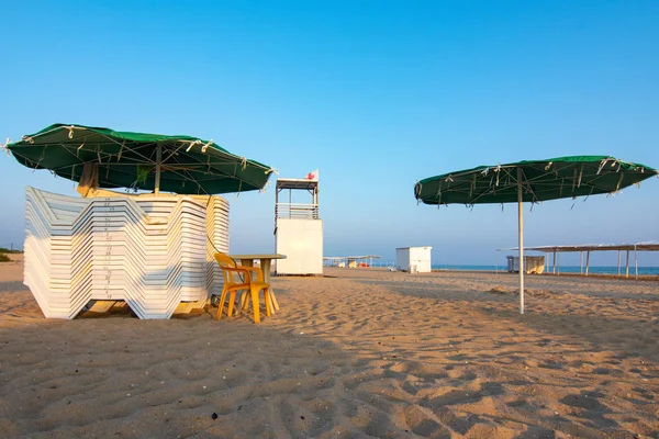 Zusammengefaltete Liegestühle und eine leere Rettungswache an einem einsamen Sandstrand bei Sonnenuntergang — Stockfoto