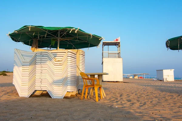 Zusammengefaltete Liegestühle und eine leere Rettungswache an einem einsamen Sandstrand — Stockfoto