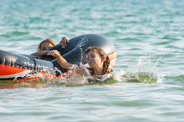 Duas meninas mergulham de um barco inflável no mar — Fotografia de Stock