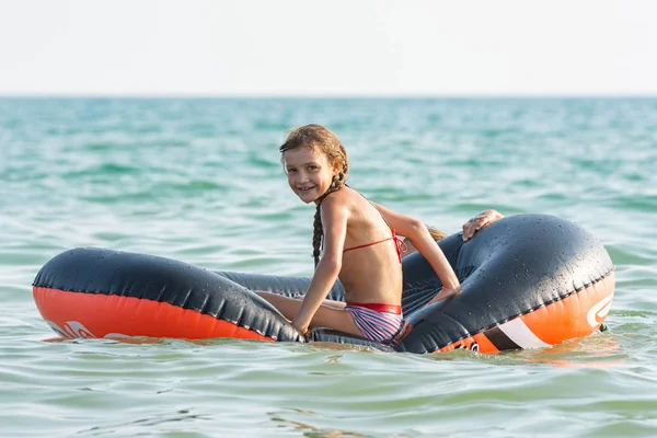 Веселая девушка катается на надувной лодке в море — стоковое фото