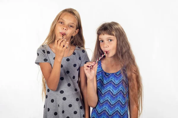 Zwei Mädchen saugen Lutscher und schauen in den Rahmen — Stockfoto