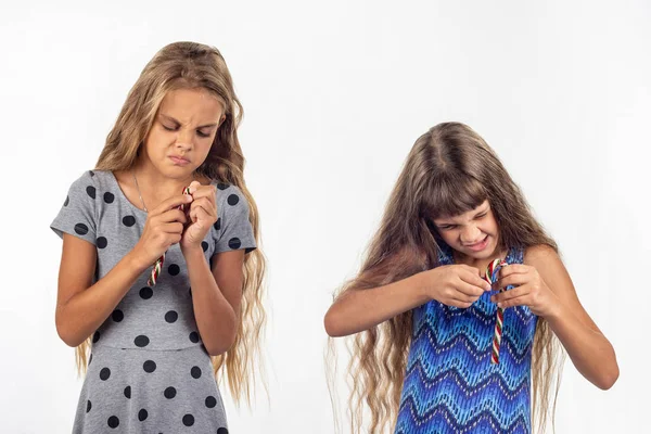 Dvě dívky se snaží otevřít plastikový pytlík s karamelovými kandama — Stock fotografie
