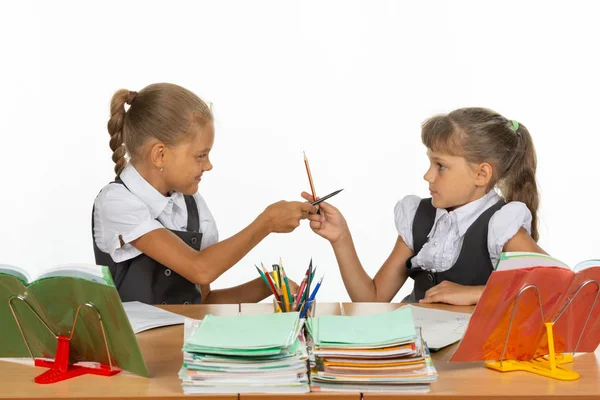 Две девушки дерутся карандашами за школьным столом — стоковое фото