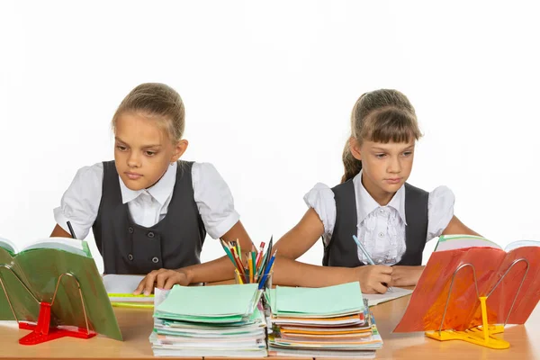 Zwei Schulmädchen sitzen an einem Schreibtisch und betrachten Schulbücher — Stockfoto