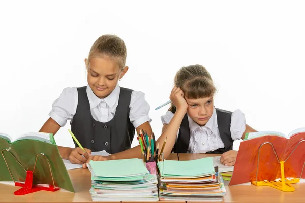 Two schoolgirls at a desk, one with a good mood, the other with a bad — Stock Photo, Image