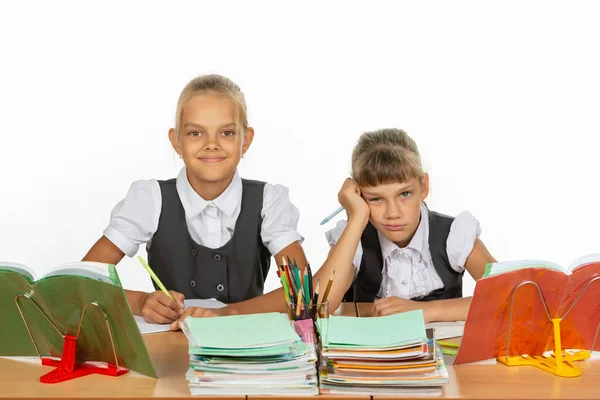 Two schoolgirls at a desk, one funny, the other upset — Stock Photo, Image
