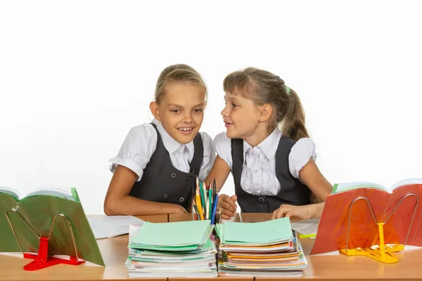 Två tjejer viskar när de sitter vid ett skrivbord — Stockfoto