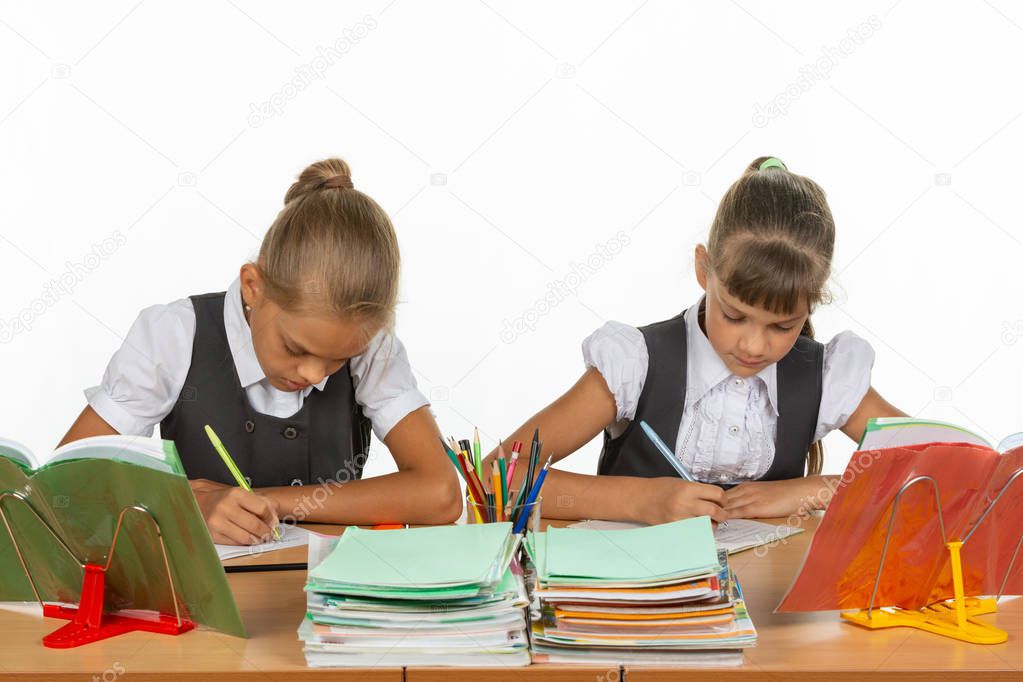 Two girls in a lesson write in a notebook