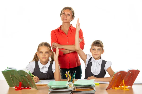 Kinderen trekken hun handen omhoog, klaar om een vraag te beantwoorden, op de achtergrond een tevreden leraar — Stockfoto