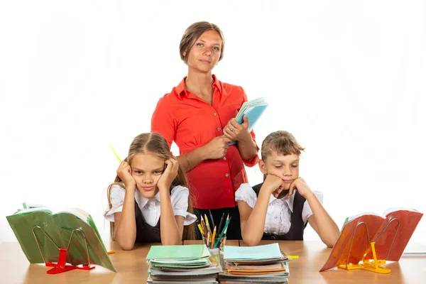 Studentesse annoiate a una scrivania, sullo sfondo un insegnante con quaderni — Foto Stock